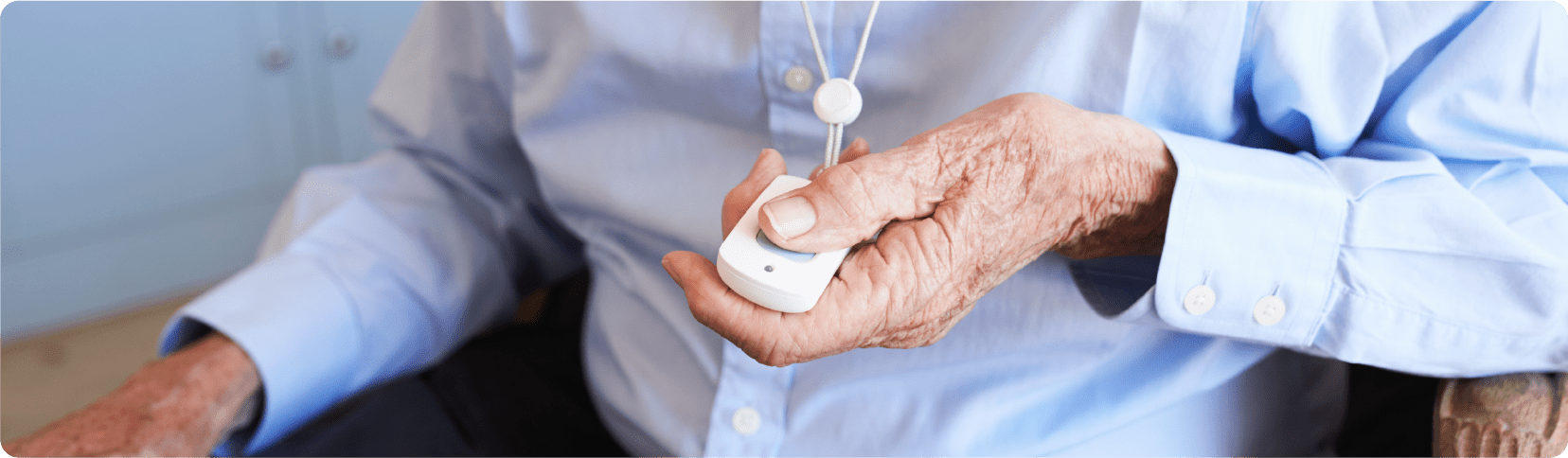 An elderly person holding a medical alert pendant during dementia action week.