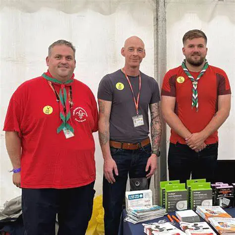 Three men behind a table with Scout badges, items, and a sign about CO awareness.