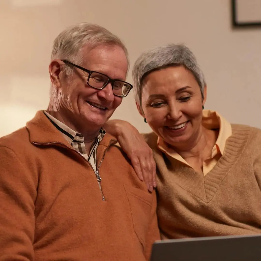 Older couple smiling together indoors, learning winter safety tips in the West Midlands.