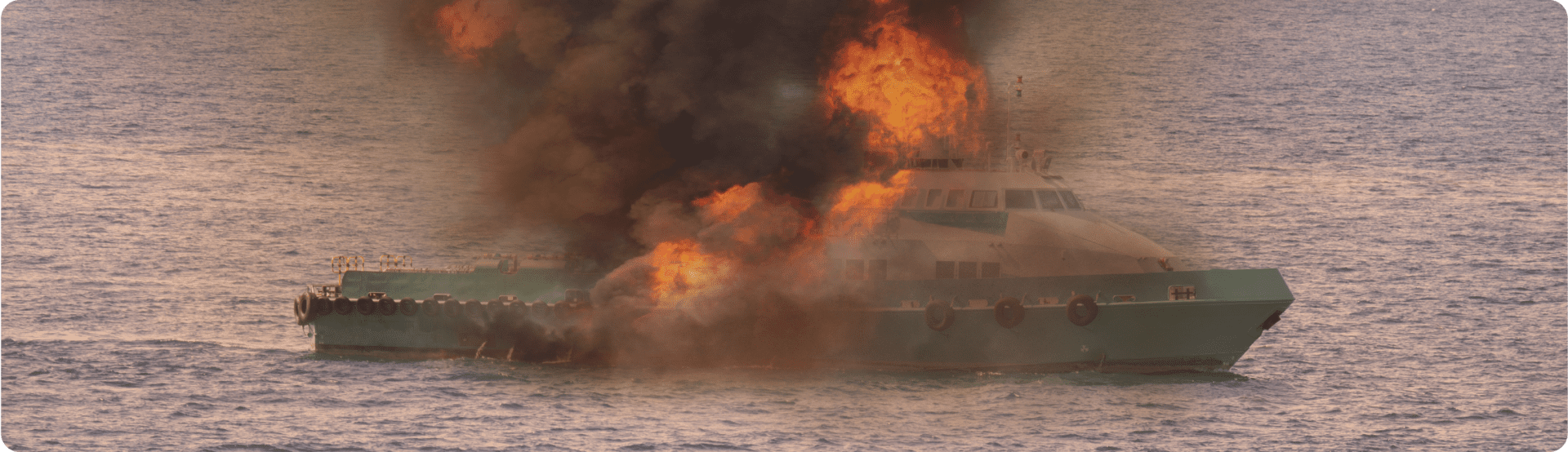 A boat on the ocean engulfed in flames—remember boat safety week.