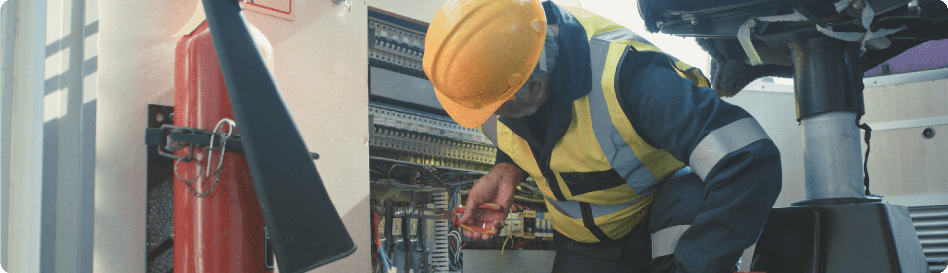 Worker in a yellow hard hat inspects electrical gear, promoting Boat Safety Week awareness.