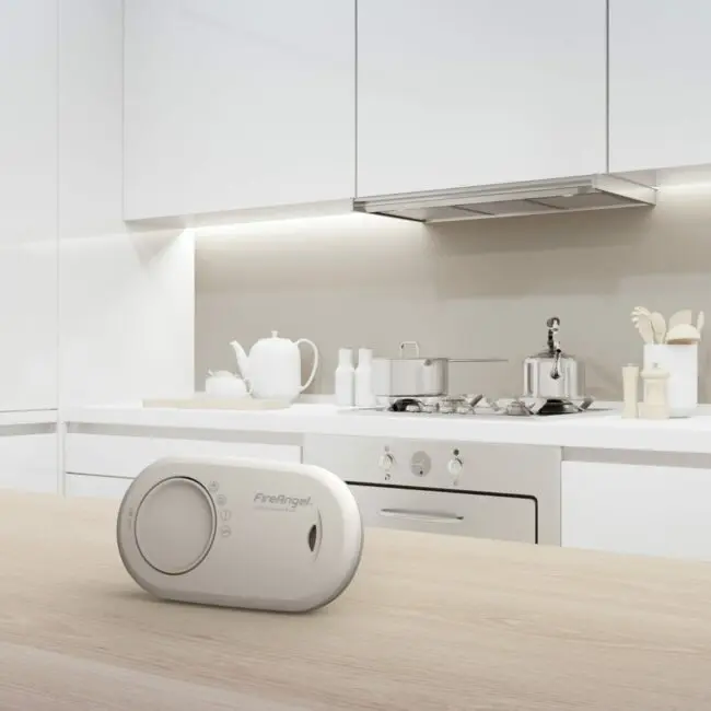 The FA3820X4 carbon monoxide alarm sits on a wooden worktop in a modern white kitchen.