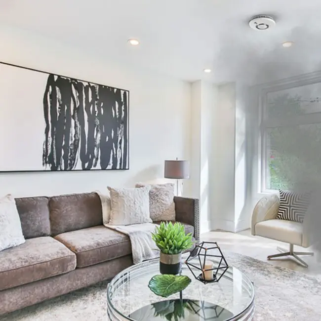 Modern living room with smoke from the window and an FS2126-T smoke detector on the ceiling.