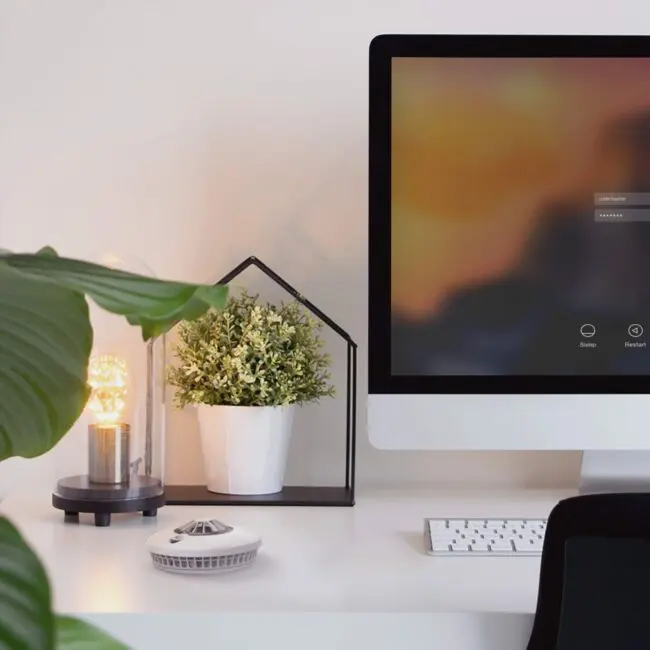 A modern desk with an HT-630, computer, potted plant, lamp, and keyboard.