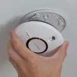 A person installs or removes an ST-750T smoke detector from a ceiling mounting.