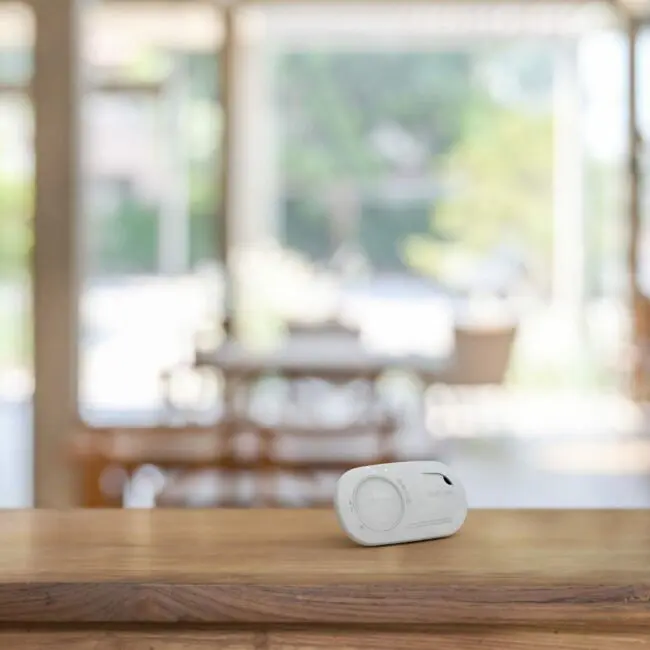The FA3328-EUT carbon monoxide alarm sits on a wooden table with a blurred indoor background.