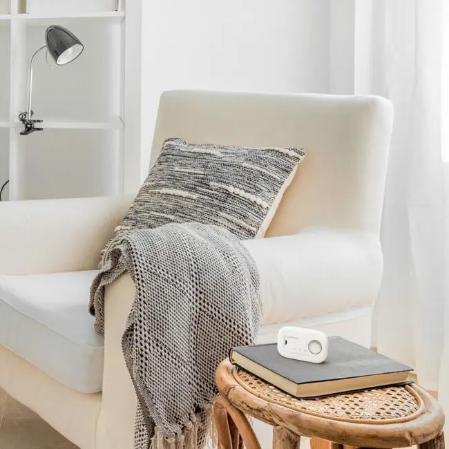FA6813 cream armchair with cushion, blanket, table, books, and a plug adaptor nearby.