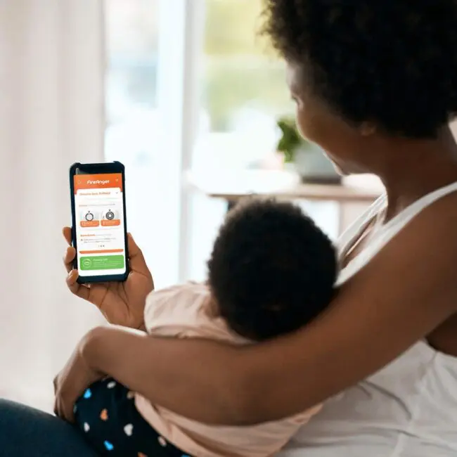 Woman with baby checks health tracking info on FP1000W2-R smartphone app.