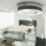 FP1640W2-R smoke detector mounted on ceiling in a modern living room, close-up.