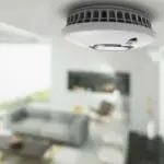 The FP2620W2-R smoke detector is mounted on a ceiling in a modern lounge.