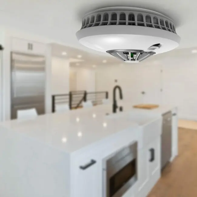 FS1226-T smoke detector mounted on the ceiling in a modern kitchen, close-up view.