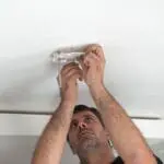 Man uses HM-SN-1 to install or repair a ceiling fitting.