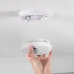 Hand installing or removing an RF-BW-T smoke detector from a ceiling mount.