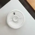 SB1-R smoke alarm on a white ceiling near wood.