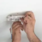 Hands installing an HM-SN-1 ceiling fitting with exposed wires and a white mounting plate.