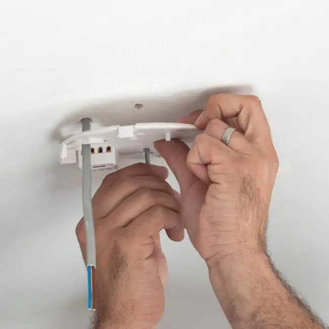 Hands installing an HM-SN-1 ceiling fitting with exposed wires and a white mounting plate.