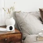 FA3322 bedside table with vase, device, book, and cup beside a tidy bed.