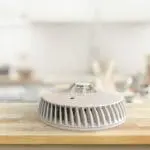 A white FA6720-R air purifier sits on a wooden kitchen worktop with a blurred background.