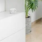 An FA6813 sits on a white cupboard next to a potted plant indoors.