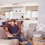Father and son with laptop; FP1014W2-R smart switch in kitchen with mother and daughter.