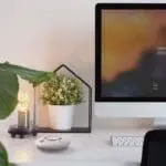 Modern desk setup featuring the FP2620W2-R, computer, lamp, and potted plant on white surface.