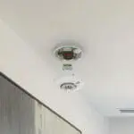 An FS1226-T smoke detector is off the ceiling, revealing its internal parts.