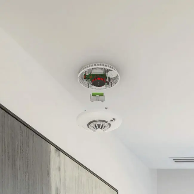An FS1226-T smoke detector is off the ceiling, revealing its internal parts.