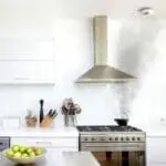 A kitchen with a FireAngel HT-630 and a steaming kettle under the cooker hood.