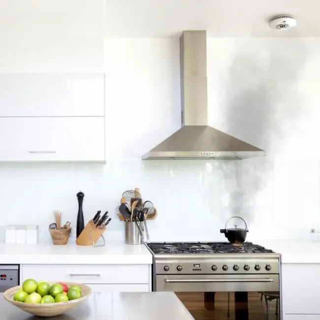 A kitchen with a FireAngel HT-630 and a steaming kettle under the cooker hood.