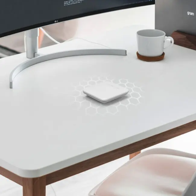 White desk with monitor, cup, coaster, and FP1000W2-R device in the centre.
