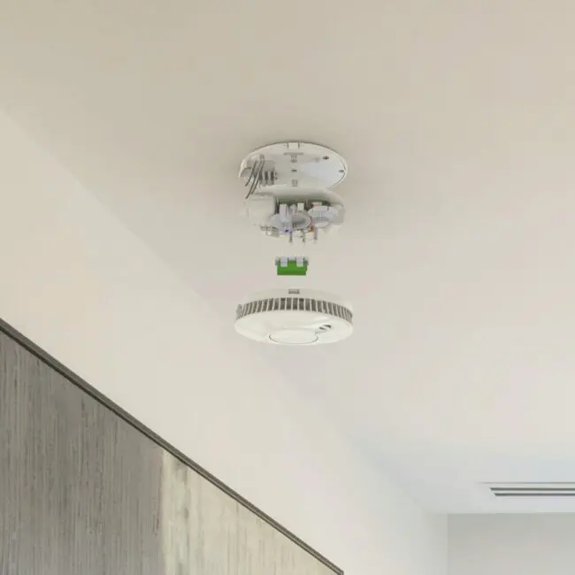 The FP1640W2-R smoke detector hangs open, exposing its internal wiring and parts.