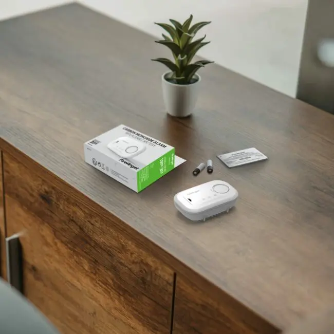 FA6813, box, and batteries on a wooden cupboard beside a small potted plant.