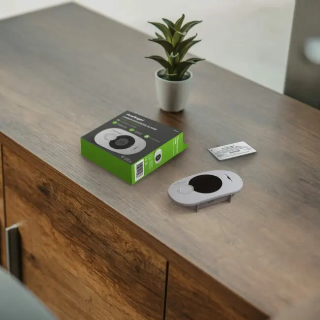 An FA3322 metre, box, and instructions sit on a wooden cupboard next to a small plant.