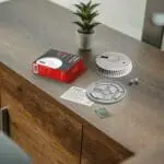 FA6611-R smoke detector kit with parts and instructions on a desk near a small potted plant.