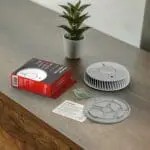 FA6620-R smoke detector, box, mounting kit, and plant on a wooden table.