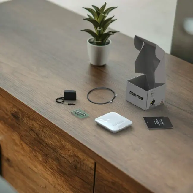 FP1000W2-R gadget kit and a small plant on a wooden table.