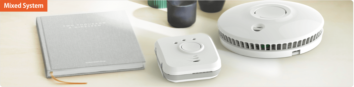 Two interlinking proconnected alarms sit beside a closed grey book on a light surface.