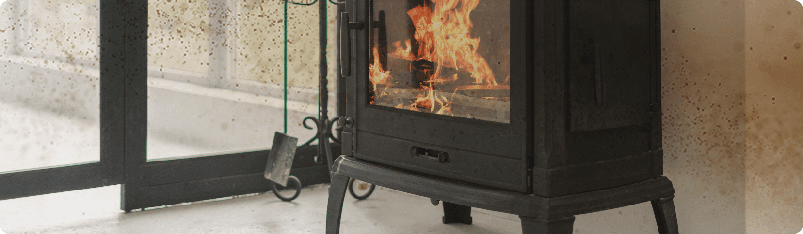 A black wood-burning stove with fire, next to a glass door, meets CO alarm regulations.