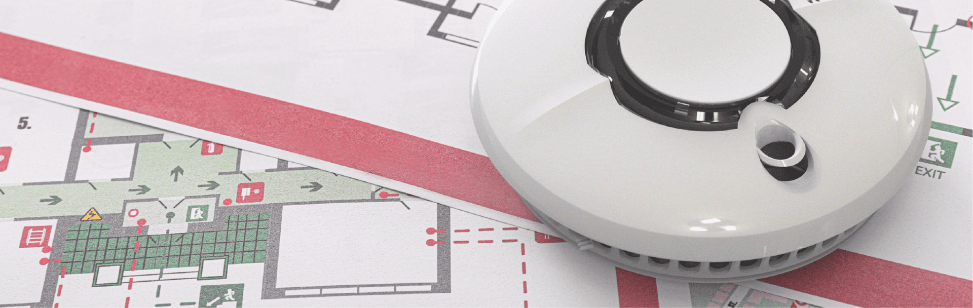 A smoke detector atop an evacuation map, complying with new regulations for safety.