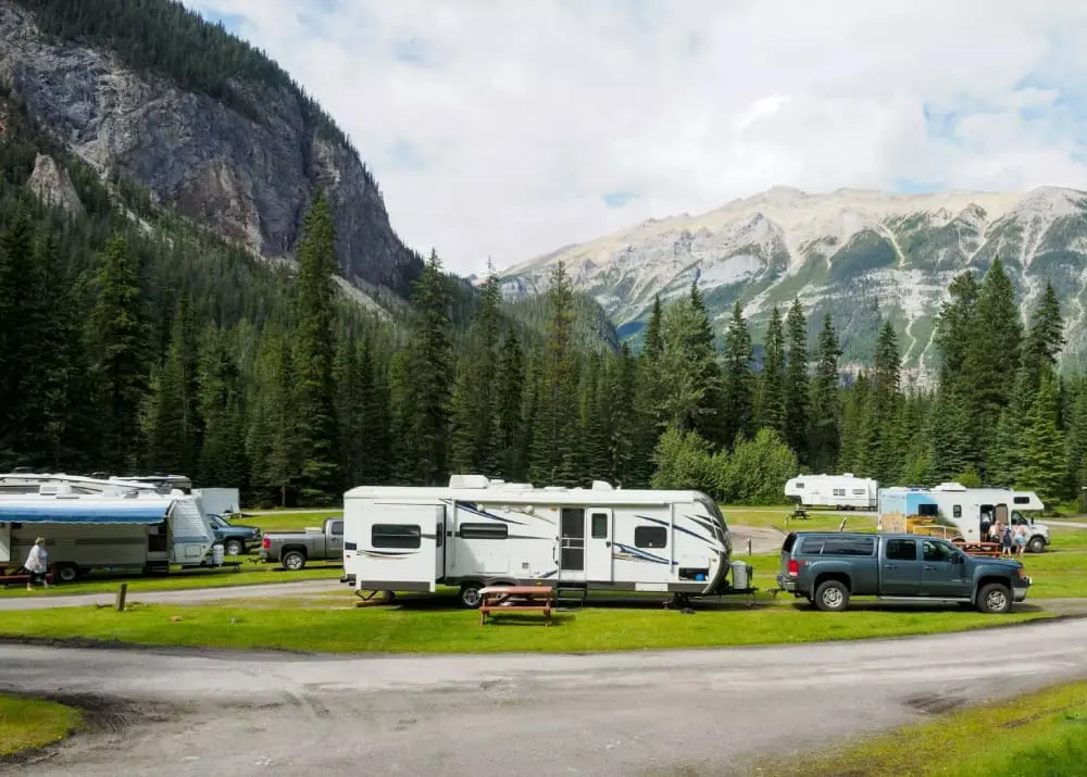 Several campervans and a lorry parked at a campsite, showcasing caravan safety in the mountains.