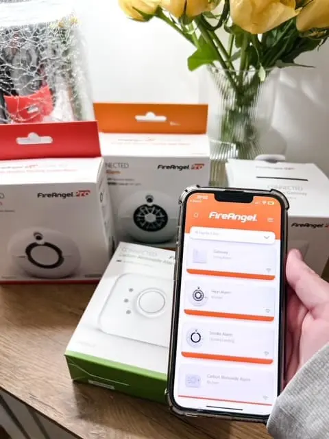 A hand holds a phone with the FireAngel app, highlighting home safety with FireAngel alarms.
