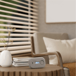 A compact FA6812-EUX10 device sits on a table near books in a cosy, neutral-toned living room.