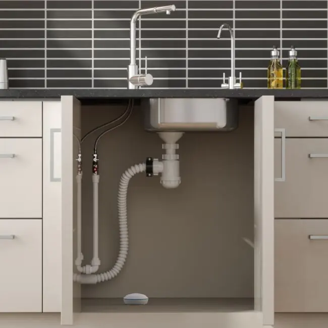 Kitchen sink cupboard open to show pipes and FA7011-EUX4 under the sink.