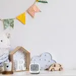 Nursery shelf with toys, an FA7312-EUX4 digital thermometer, and a colourful pennant bunting.