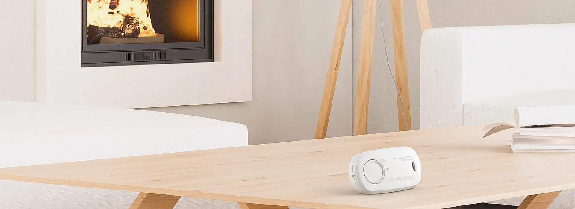 A CO alarm placed on a coffee table that's in a living room, with a wood burning fireplace.