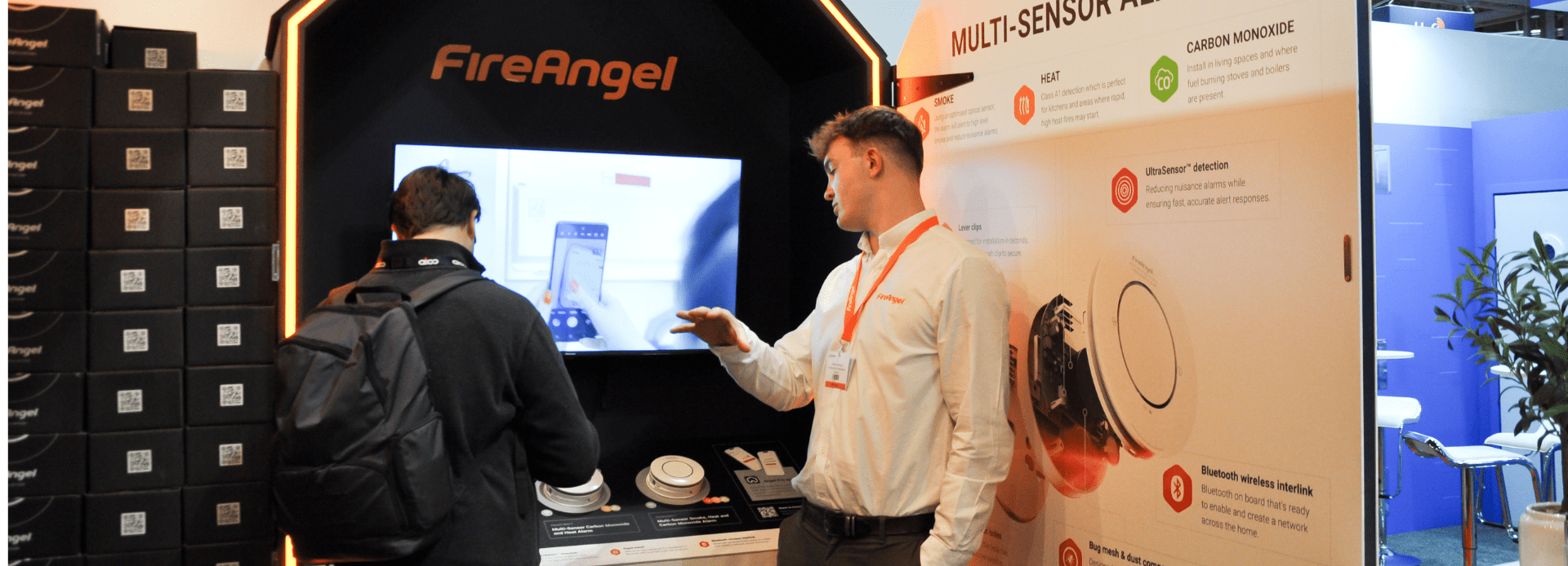 Two people at the FireAngel stand discuss fire safety products at a Fire Safety Event.