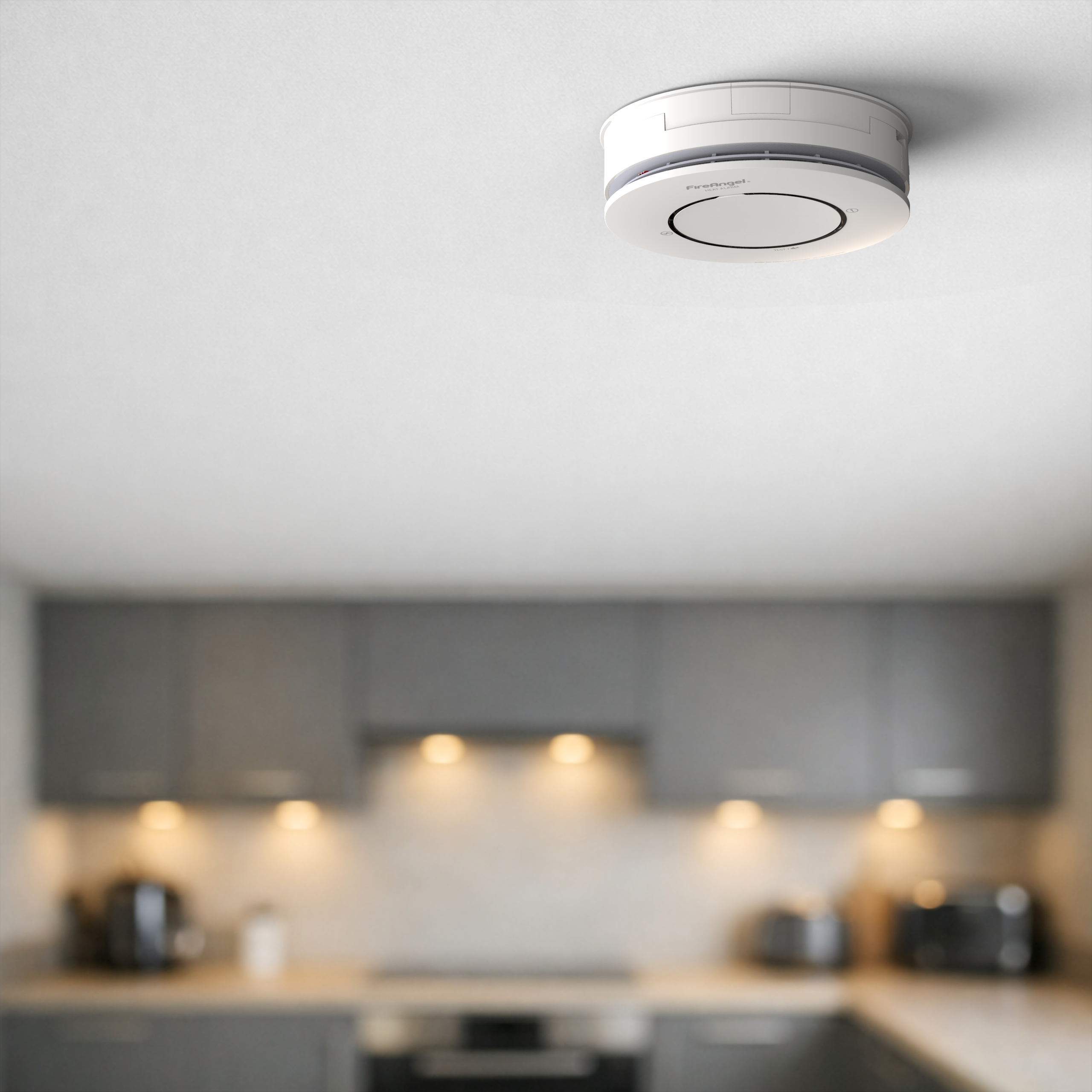 Spec+ Heat Alarm on a white ceiling in a kitchen with grey cabinets and appliances.