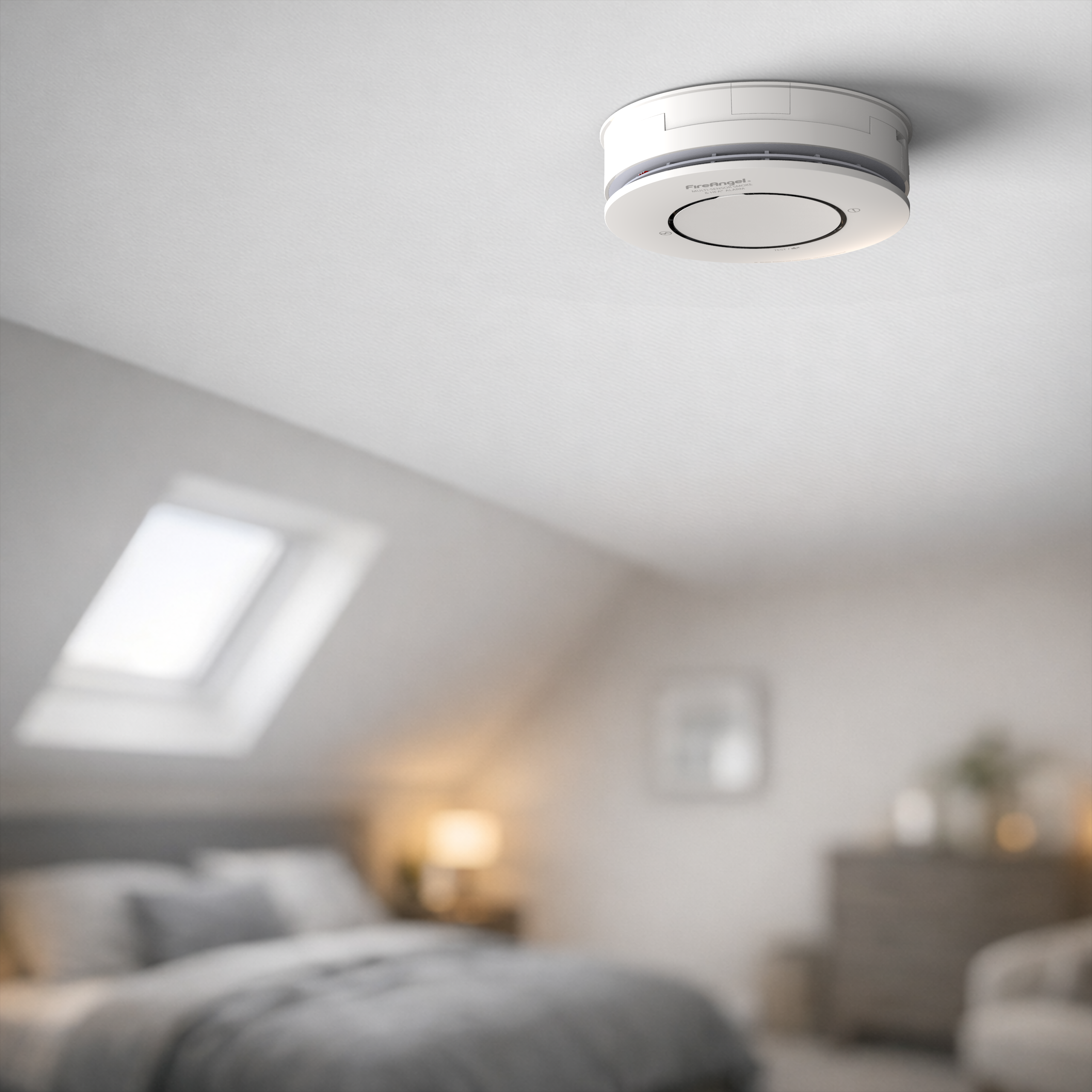 Spec+ Smoke & Heat Alarm on a bedroom ceiling with soft light and a slanted window nearby.