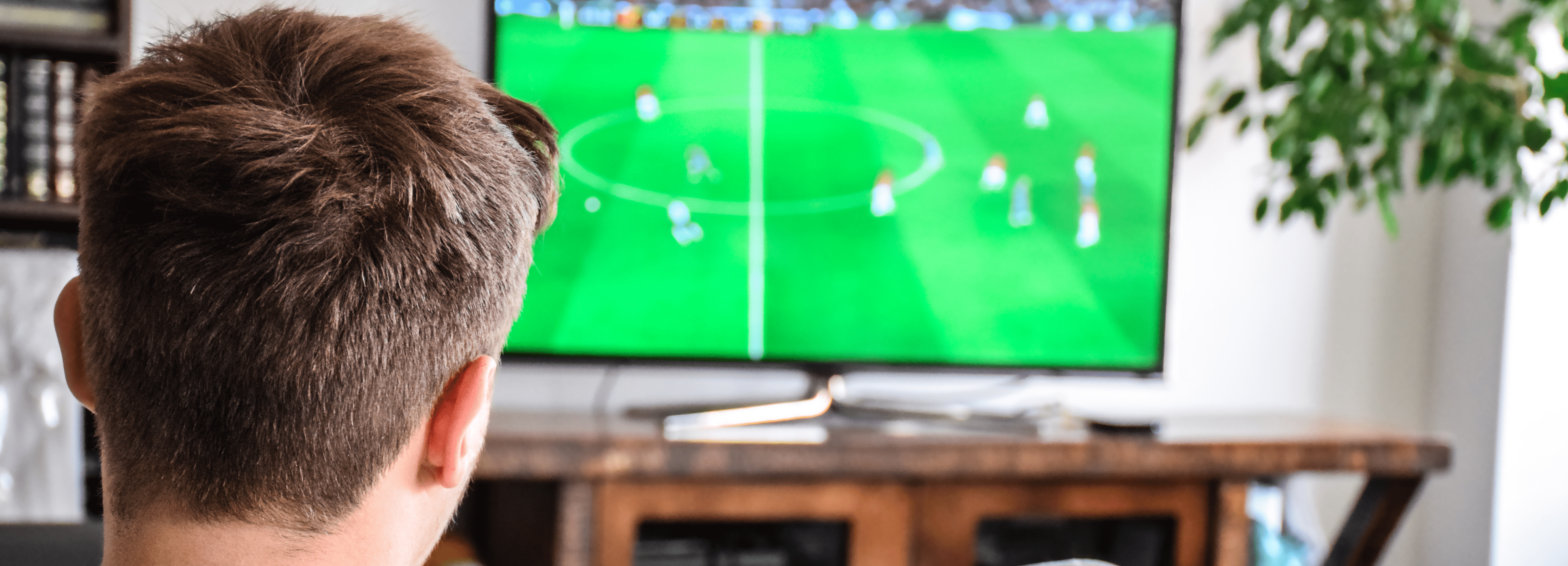 Person hosting the games watches a football match on TV in their cosy living room.