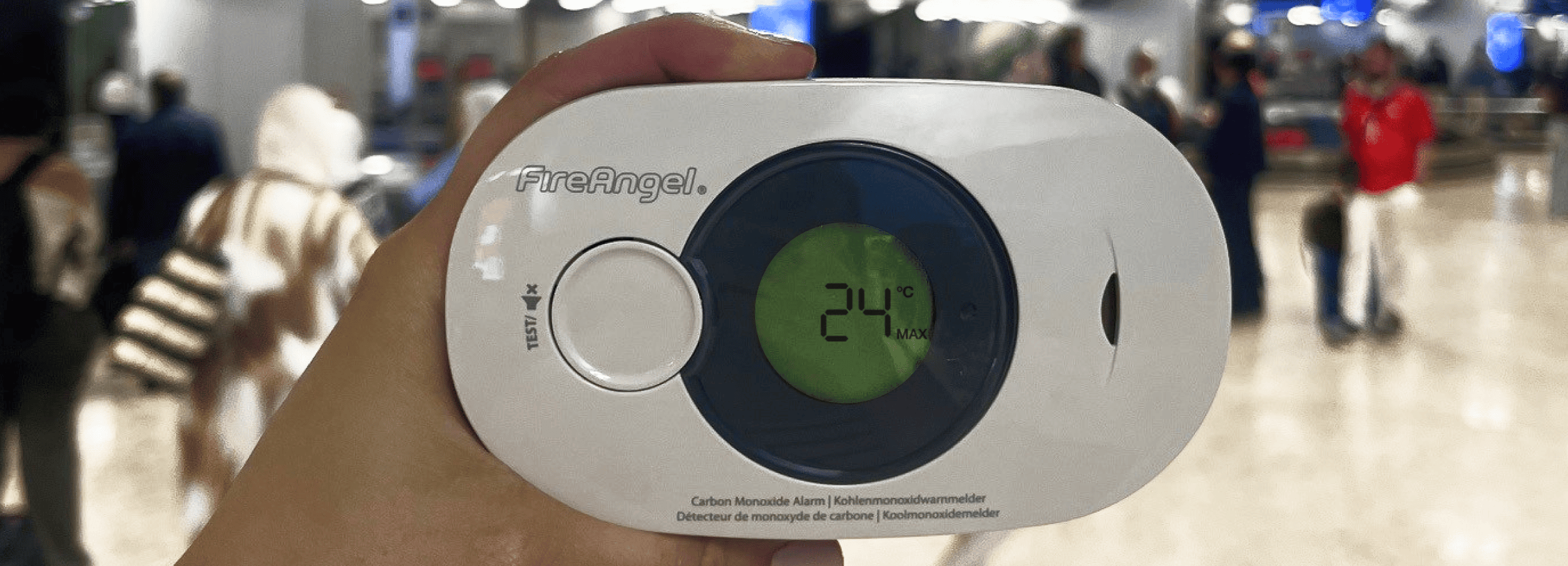 Hand holds FireAngel carbon monoxide alarm at 24°C; a reminder for summer fire safety indoors.